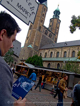 Vorne am Linken Rand ist ein Mann mit dem GöTe in der Hand im Hintergrund die Marktkirche St. Cosmas und Damian